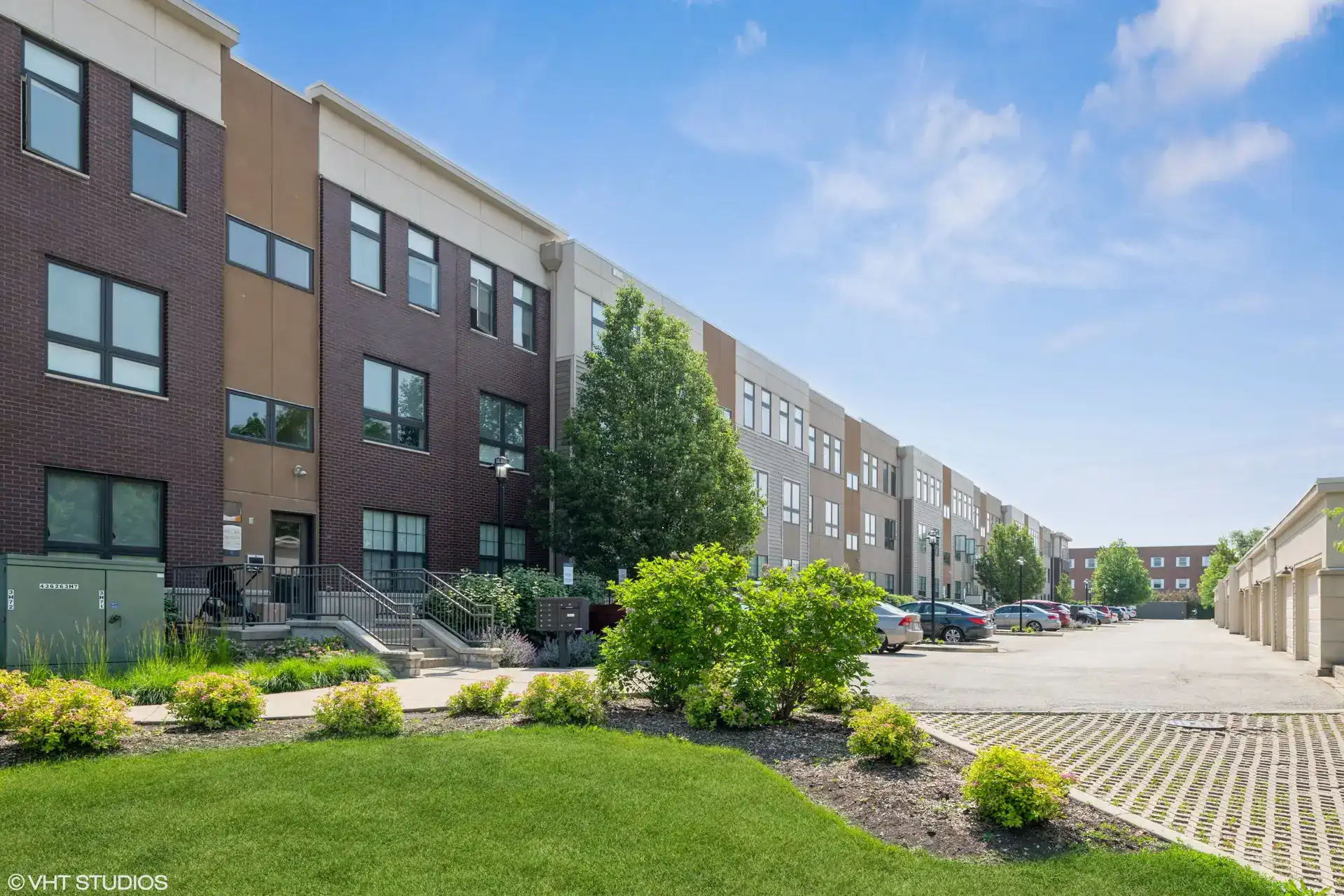 The Parker red brick and tan flat stone exterior with parking lot and detached garage parking spaces.